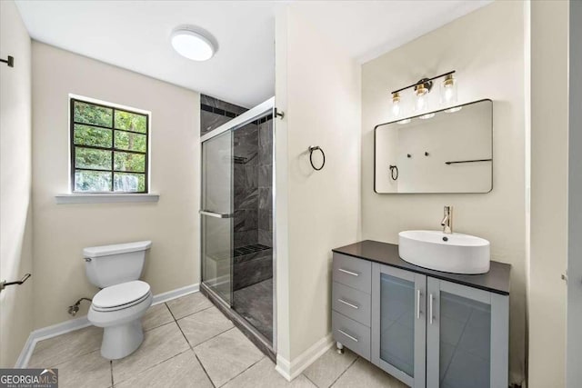 bathroom with vanity, tile patterned flooring, a shower with door, and toilet