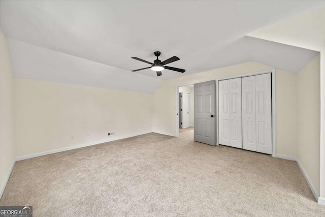 unfurnished bedroom featuring vaulted ceiling, light colored carpet, and ceiling fan