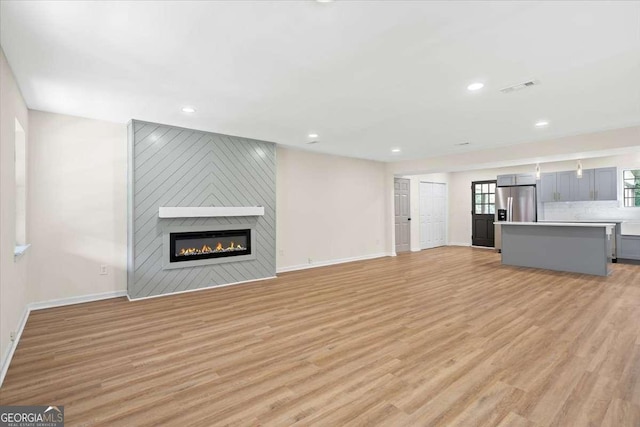 unfurnished living room featuring light wood-type flooring and a fireplace