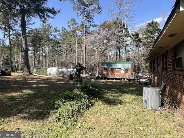 view of yard featuring central AC unit and an outdoor structure