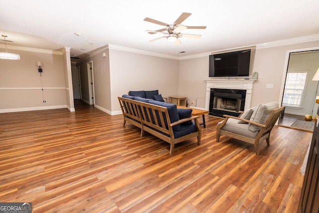 living room with wood-type flooring, ornamental molding, and ceiling fan