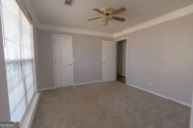 empty room featuring crown molding, carpet floors, and ceiling fan