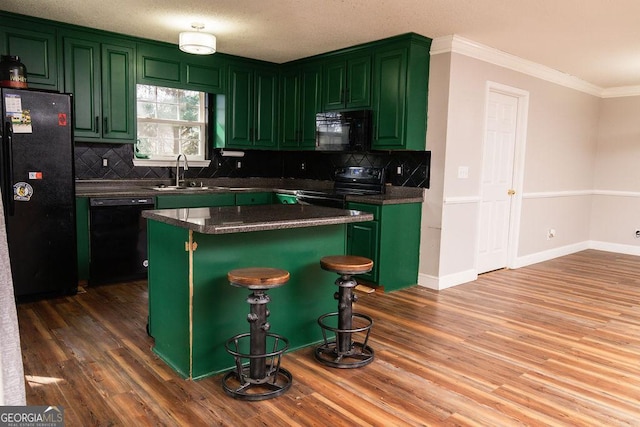 kitchen with sink, dark wood-type flooring, a kitchen breakfast bar, a center island, and black appliances