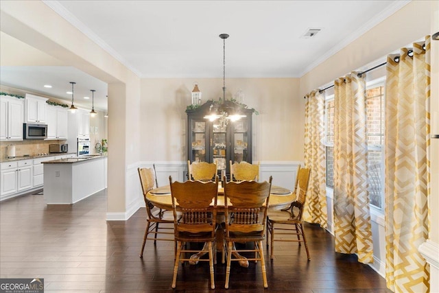 dining space featuring an inviting chandelier, ornamental molding, and dark hardwood / wood-style floors