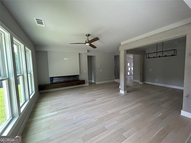 unfurnished living room featuring ceiling fan, plenty of natural light, and light hardwood / wood-style flooring