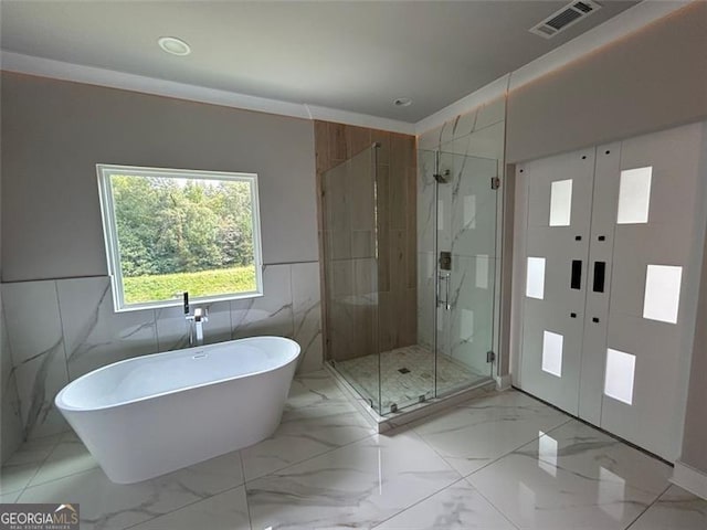 bathroom featuring french doors, shower with separate bathtub, and tile walls