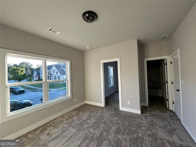 unfurnished bedroom with dark carpet