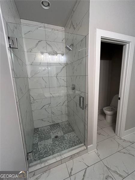 bathroom with a shower with shower door and toilet