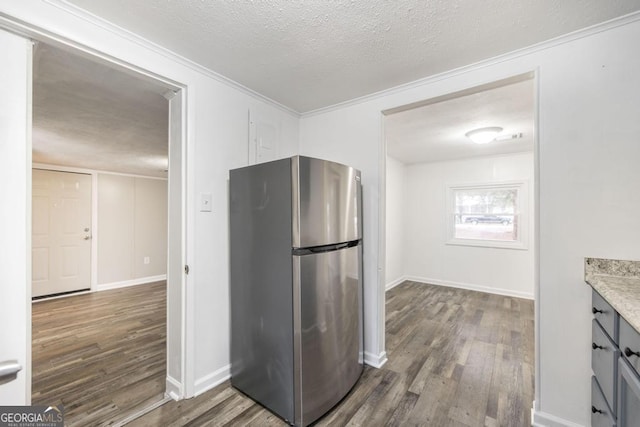 kitchen featuring ornamental molding, dark hardwood / wood-style floors, a textured ceiling, and stainless steel refrigerator