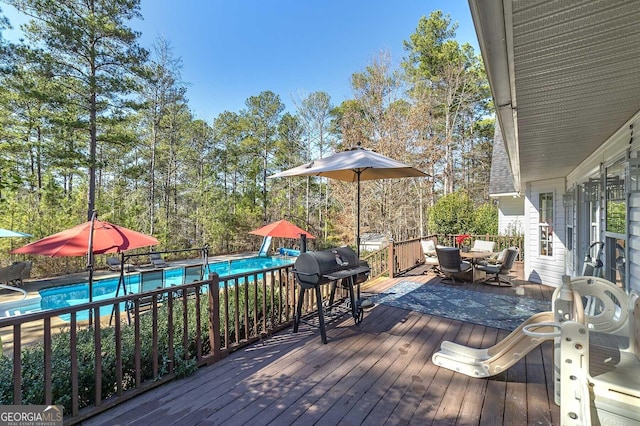 wooden terrace featuring grilling area and a fenced in pool