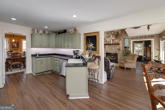 kitchen with green cabinetry, dishwasher, a breakfast bar area, and kitchen peninsula