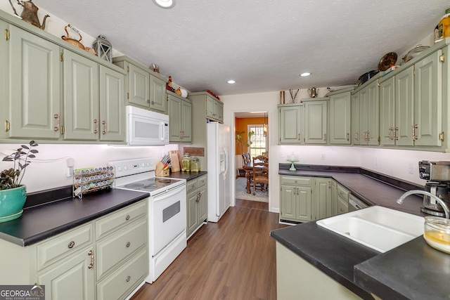 kitchen with dark hardwood / wood-style floors, sink, a textured ceiling, and white appliances