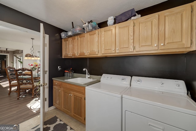 washroom featuring sink, washer and clothes dryer, cabinets, and a textured ceiling