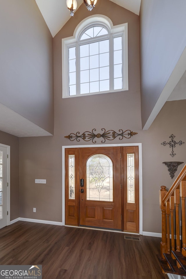 foyer featuring high vaulted ceiling, dark wood-type flooring, and an inviting chandelier