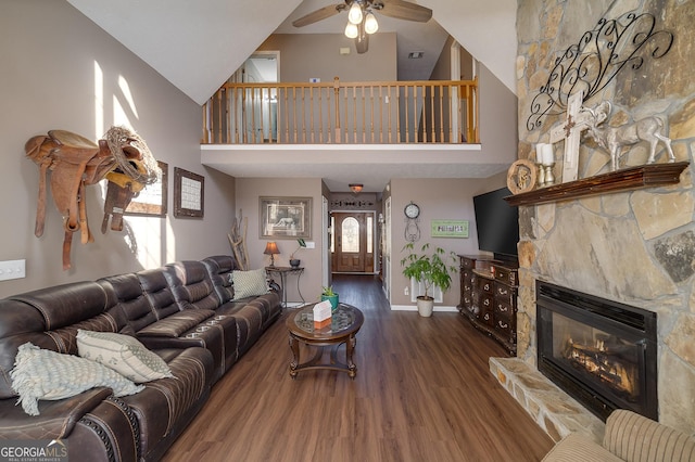 living room featuring a stone fireplace, high vaulted ceiling, dark hardwood / wood-style floors, and ceiling fan