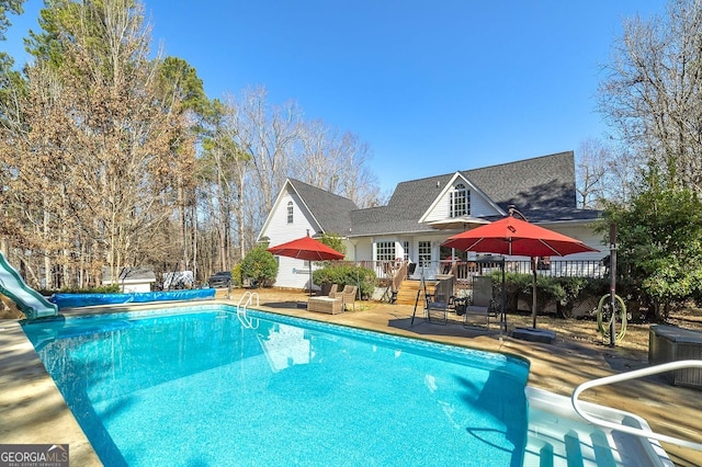 view of pool featuring a water slide, a patio, and a deck