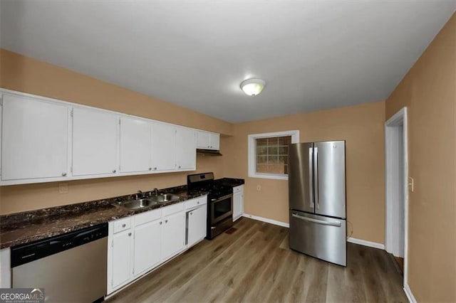 kitchen featuring sink, dark stone counters, stainless steel appliances, light hardwood / wood-style floors, and white cabinets