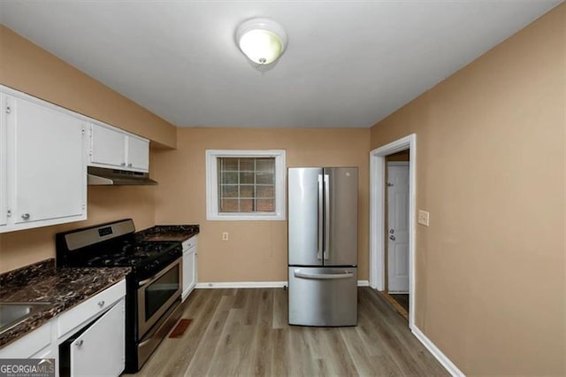 kitchen with dark stone countertops, appliances with stainless steel finishes, light hardwood / wood-style flooring, and white cabinets