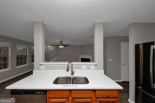 kitchen with sink, stainless steel dishwasher, black fridge, dark wood-type flooring, and a textured ceiling