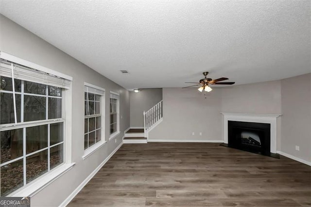 unfurnished living room with ceiling fan, dark wood-type flooring, and a textured ceiling