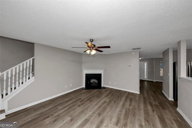 unfurnished living room featuring a textured ceiling, dark hardwood / wood-style floors, and ceiling fan