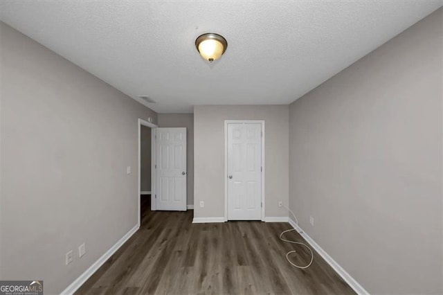 unfurnished bedroom featuring dark hardwood / wood-style floors and a textured ceiling