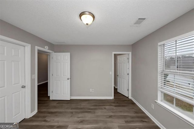 unfurnished bedroom featuring dark hardwood / wood-style flooring and a textured ceiling