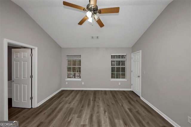 empty room with dark hardwood / wood-style flooring, vaulted ceiling, and ceiling fan