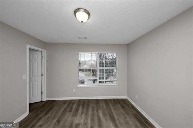 empty room featuring dark hardwood / wood-style floors and a textured ceiling