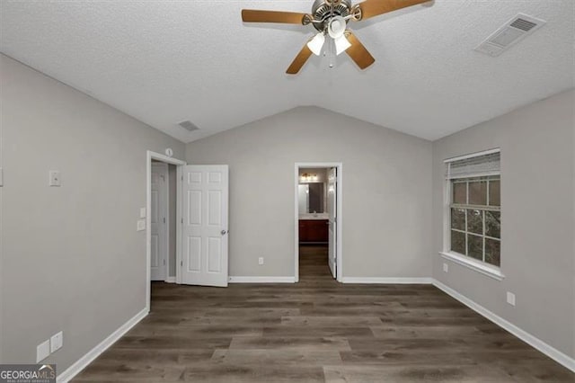 unfurnished bedroom featuring dark wood-type flooring, ceiling fan, connected bathroom, a textured ceiling, and vaulted ceiling