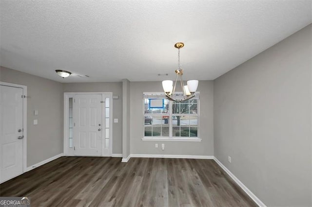 entrance foyer with an inviting chandelier, a textured ceiling, and dark hardwood / wood-style flooring