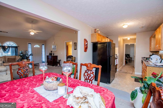 dining area featuring ceiling fan, vaulted ceiling, and a textured ceiling