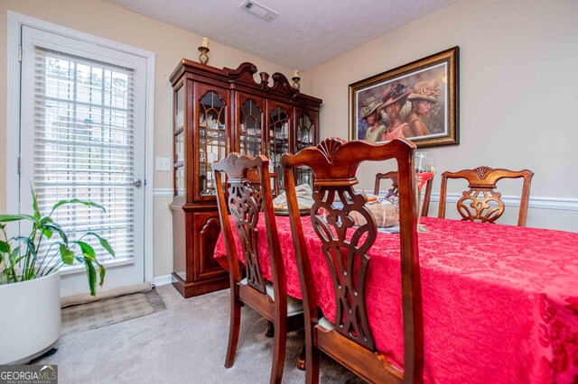 carpeted dining area featuring a textured ceiling