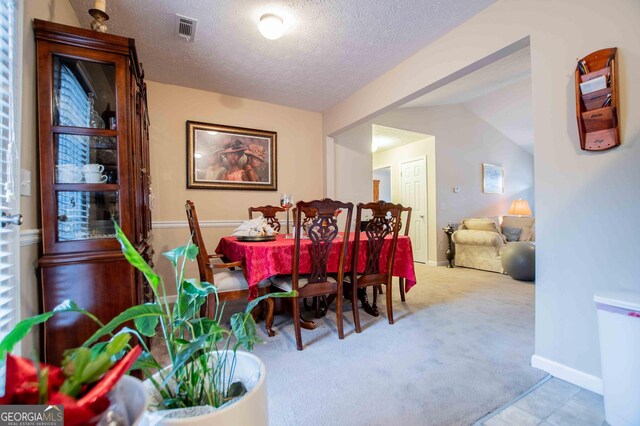 dining area featuring light carpet and a textured ceiling