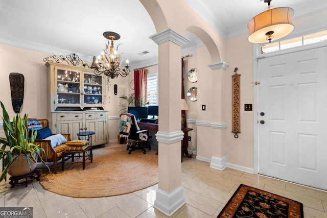 foyer entrance with a notable chandelier, crown molding, and ornate columns