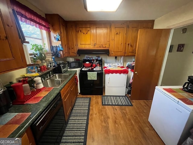 kitchen featuring washer / clothes dryer, black appliances, sink, and light wood-type flooring