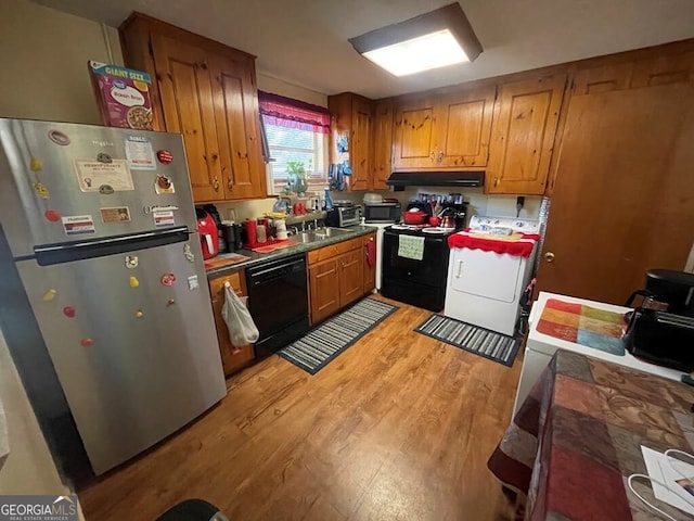 kitchen featuring washer / dryer, sink, light hardwood / wood-style floors, and black appliances