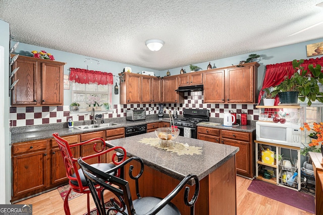 kitchen with sink, light hardwood / wood-style flooring, a center island, and black gas stove