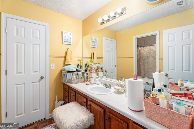 bathroom with vanity, curtained shower, and a textured ceiling