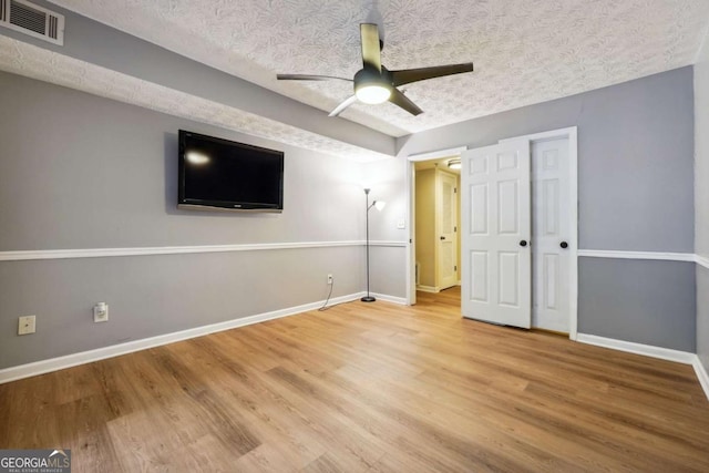 unfurnished bedroom featuring ceiling fan, wood-type flooring, a closet, and a textured ceiling