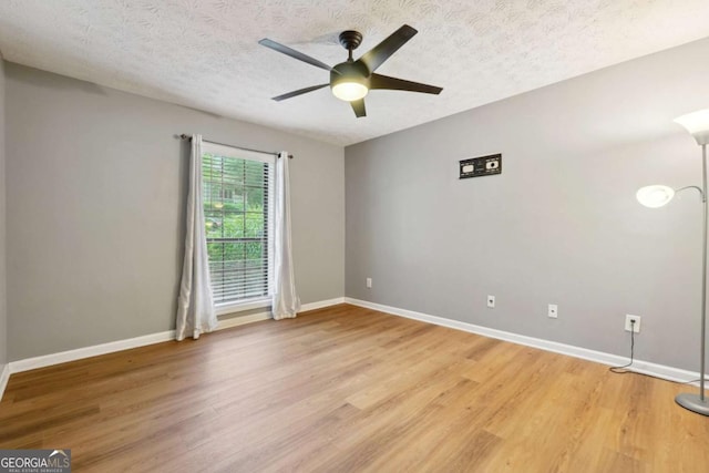 spare room with ceiling fan, a textured ceiling, and light wood-type flooring