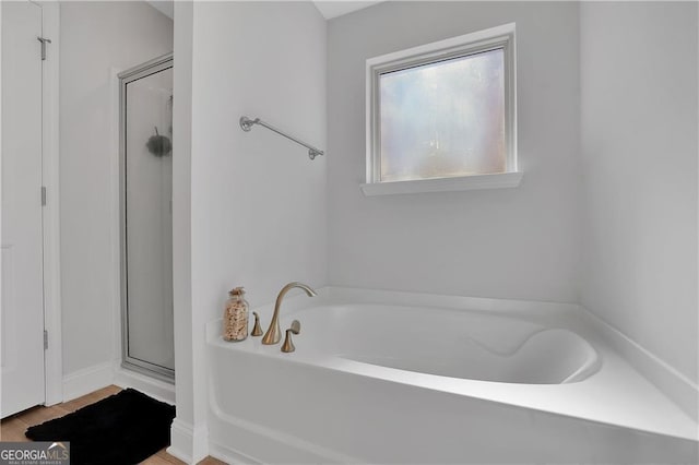 bathroom with hardwood / wood-style floors and shower with separate bathtub