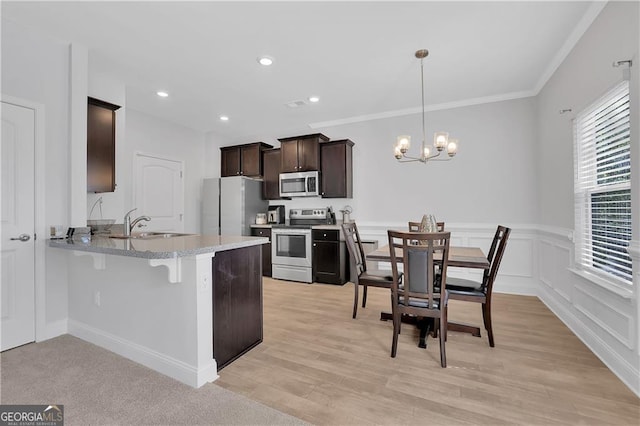 kitchen featuring appliances with stainless steel finishes, hanging light fixtures, a kitchen breakfast bar, kitchen peninsula, and a chandelier