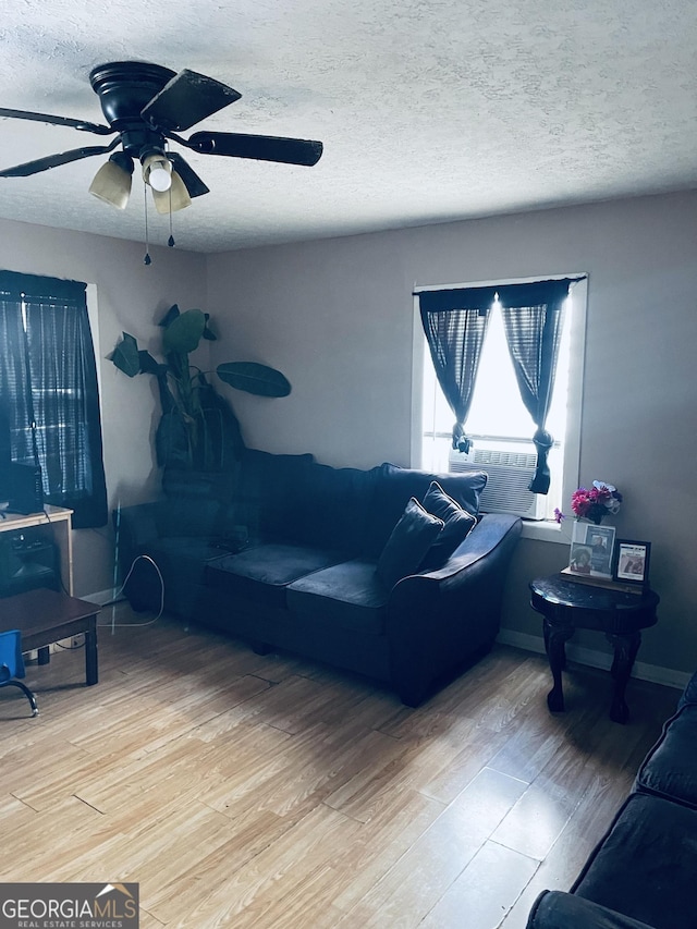 living room featuring ceiling fan, hardwood / wood-style floors, and a textured ceiling