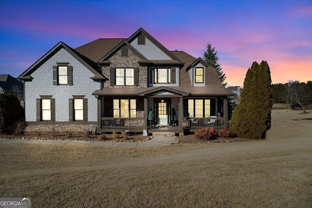 view of front of property with covered porch and a lawn