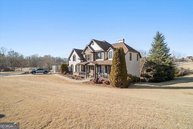 view of front of property with dirt driveway, a porch, a chimney, and a front lawn