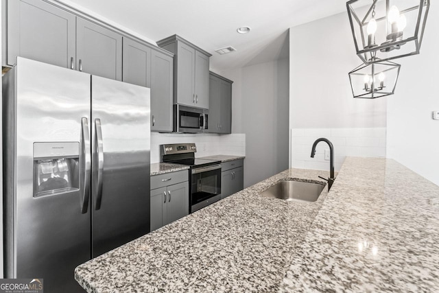 kitchen featuring sink, light stone counters, tasteful backsplash, decorative light fixtures, and stainless steel appliances