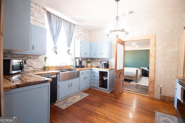 kitchen featuring decorative light fixtures, black dishwasher, sink, backsplash, and dark hardwood / wood-style flooring