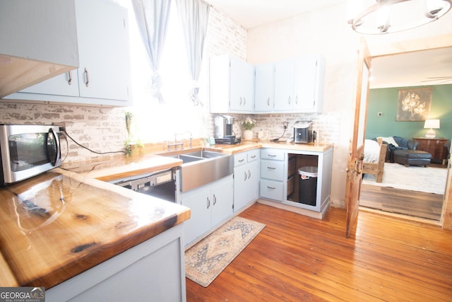 kitchen featuring wooden counters, light hardwood / wood-style floors, sink, and decorative backsplash