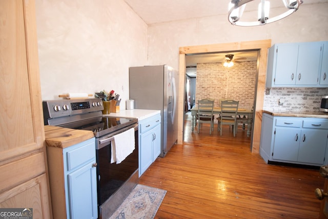 kitchen with stainless steel appliances, wood-type flooring, blue cabinetry, and butcher block countertops